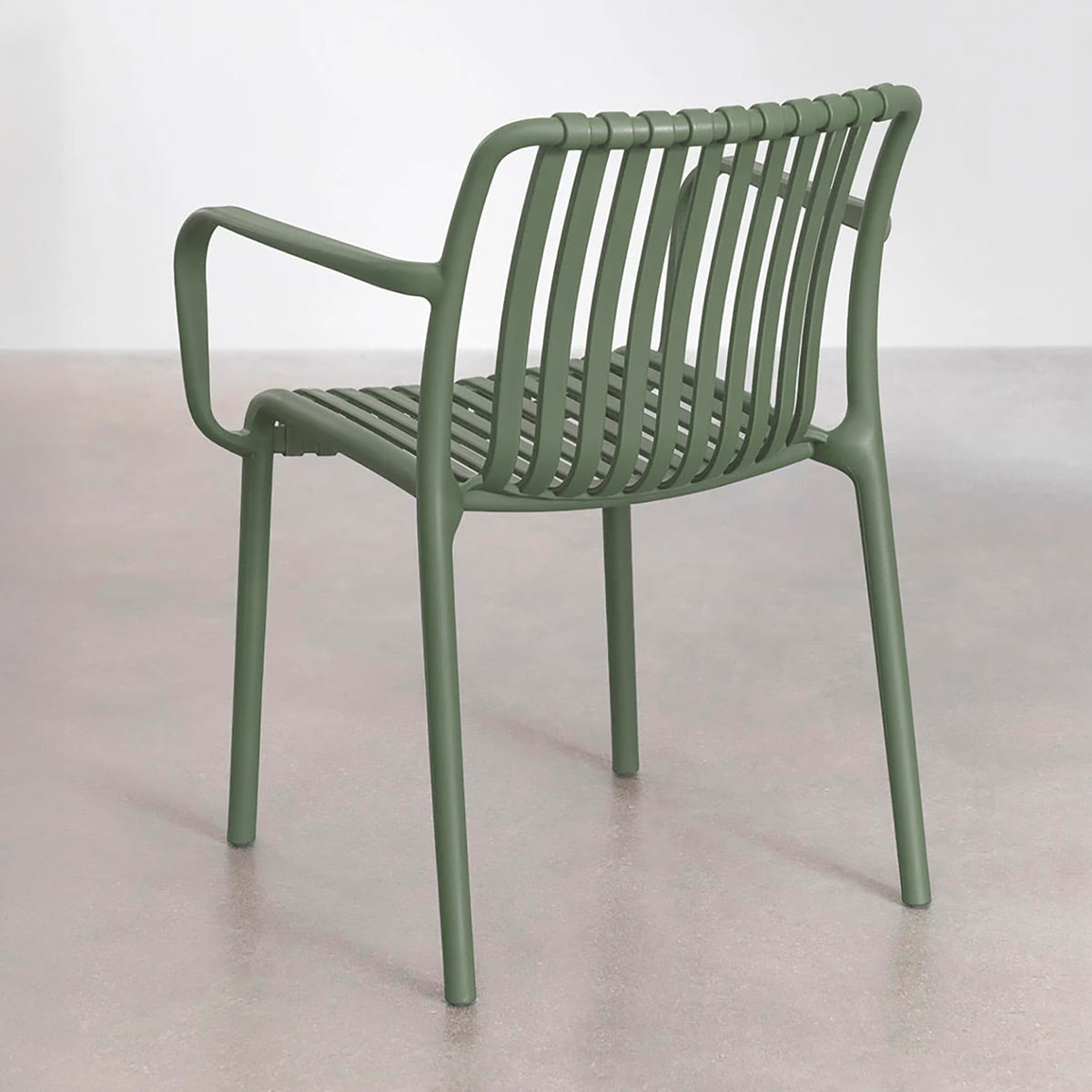 Silla de exterior Menorca verde montaje pared blanca con piso de concreto vista en perspectiva trasera